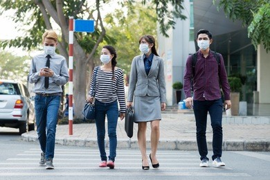asian people in moth masks crossing road in the city