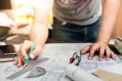 close-up of person's hand drawing plan on blue print with architect equipment
