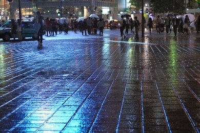 rainy pavement reflection by  night with crowd apart in tokyo metropolis, focus on pavement