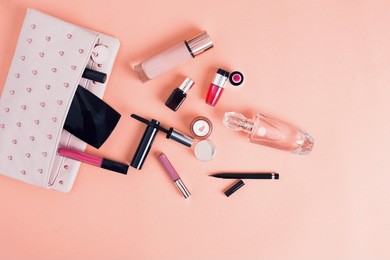 make up bag with cosmetics isolated on pink background