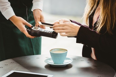 woman paying with mobile phone in cafe