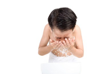 young boy wash his face by fresh water in white bathroom.