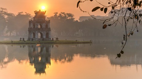 sun rising behind the turtle tower in the center of hoan kiem lake (lake of the returned sword). the lake is one of the major scenic spots in the city and serves as a focal point for its public life.