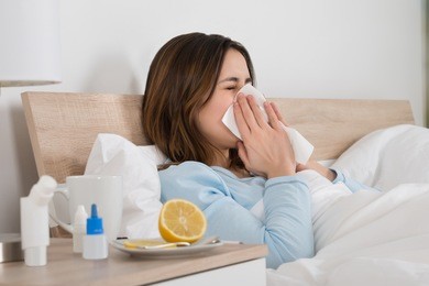 young woman infected with cold blowing her nose in handkerchief