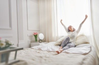 happy young woman enjoying sunny morning on the bed 