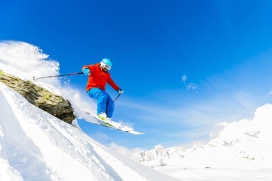 ski freerider jumping from the rock in fresh powder snow in alps.