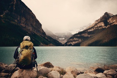 a female hiker at lake louise in banff national park with mountains and forest in canada.