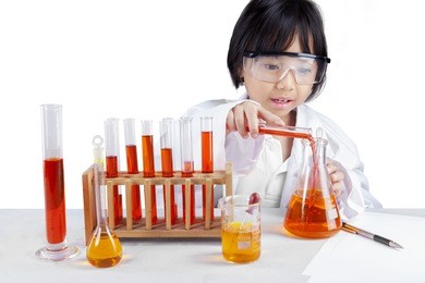portrait of little schoolgirl wearing lab coat and doing research, isolated on white background