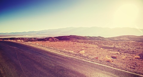 vintage toned sunset over desert road, travel background.