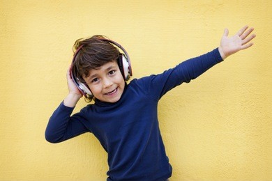 kid using headphones on yellow wall