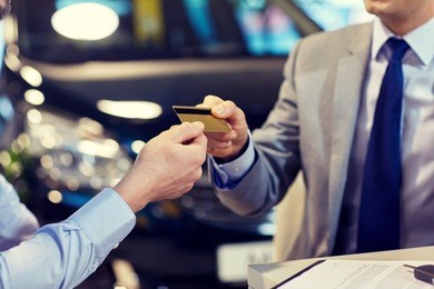 auto business, sale and people concept - close up of customer giving credit card to car dealer in auto show or salon