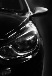 black car in patches of light on black background