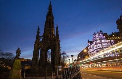 a view of the scott monument and traffic trails traveling down princes street in edinburgh, scotland.