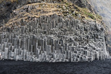 black sand beach in iceland with rock lava mountain.