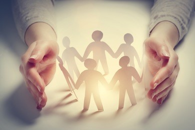 paper people surrounded by hands in gesture of protection. concept of insurance, social protection and support. 