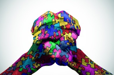 man hands put together patterned with many puzzle pieces of different colors, symbol of the autism awareness, with a slight vignette added