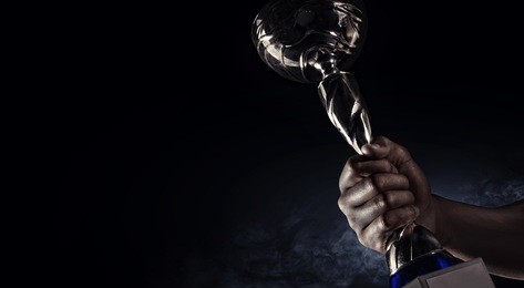 sport. man's hand holding up a gold trophy cup as a winner in a competition 