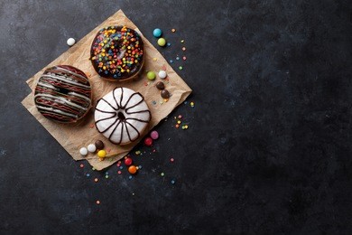 colorful donuts and candies on stone table. top view with copy space