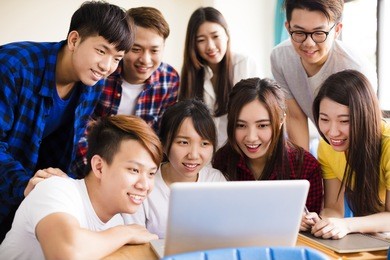 group of college students watching laptop in classroom