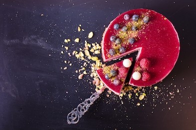 delicious raspberry cake with fresh strawberries, raspberries, blueberry, currants and pistachios on wooden background. free space for your text.