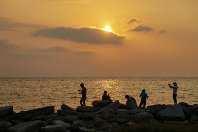 silhouette of group of people hanging out and enjoy sunset at tanjung aru beach,kota kinabalu,sabah.