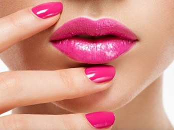 closeup woman hand with pink nails near lips. fingernails with pink manicure