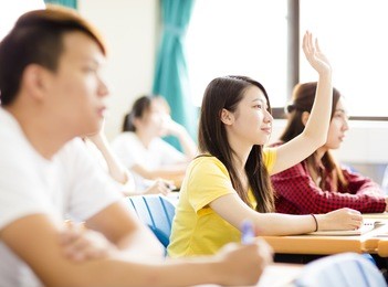 female college student raise hand for question in classroom