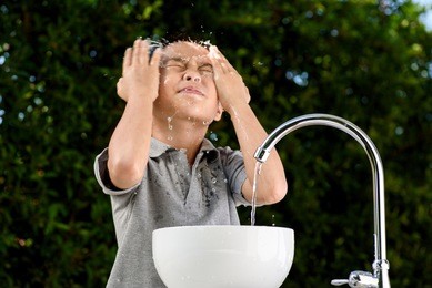 young asian boy washing his face by water from the brand new faucet.