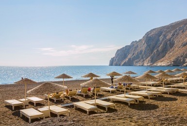 beach chairs and umbrellas on kamari beach on volcanic island santorini  in the morning, greece, summertime