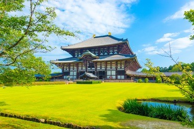 wide green lawn in front entrance facade on grounds of main great buddha hall, daibutsuden, on a beautiful, blue sky summer morning at todai-ji temple in nara, japan. horizontal