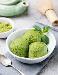 green tea matcha ice cream scoop in white bowl on a grey stone background