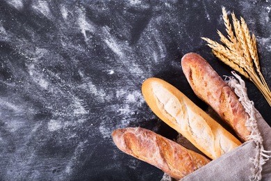 bread with wheat ears on dark board with flour, top view