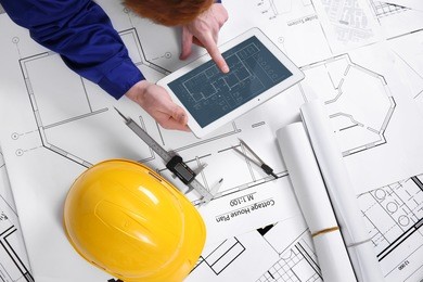 man using tablet on a blueprint