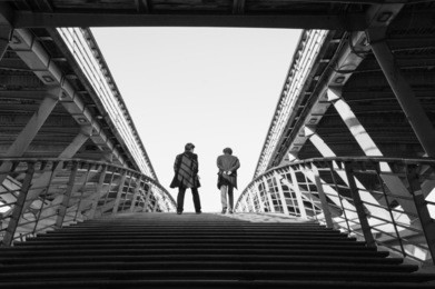 two man on pedestrian solferino bridge over seine river near orsey's museum. paris, france. back view.