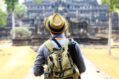 young traveler wearing a hat with backpack and tripod - at angkor wat, siem reap, cambodia