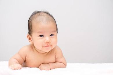 asian baby lying on stomach and raising his head