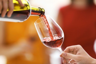 pouring red wine from bottle into glass, close up