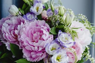 rich bunch of pink peonies and lilac eustoma roses flowers, green leaf in glass vase. fresh spring bouquet. summer background