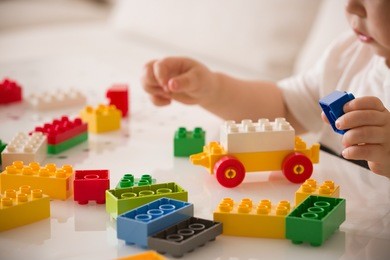 close up of child's hands playing with colorful plastic bricks at the table. toddler having fun and building out of bright constructor bricks. early learning.  developing toys