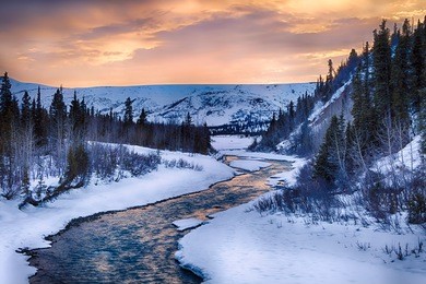 a dramatic sunset illuminates the clear waters of phelan creek in early spring in the alaska range