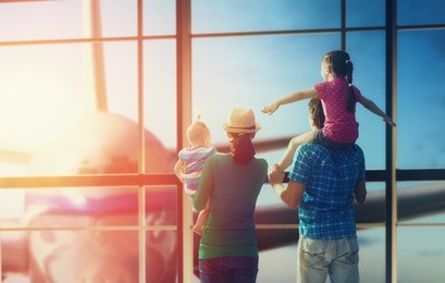happy family with children at the airport. parents and their children look out the window at the plane.