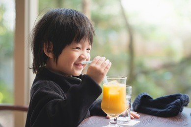 cute asian child drinking fresh orange juice