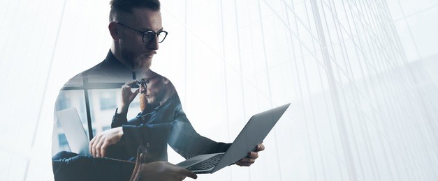 double exposure bearded businessman wearing black shirt and glasses,holding contemporary notebook hands. portrait young banker using laptop in modern office, skyscraper background. wide