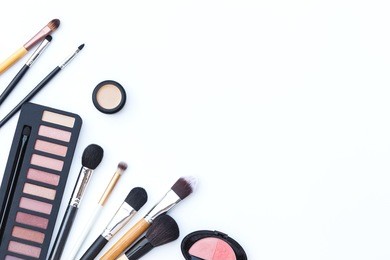flat lay photo of makeup brush and cosmetics on white background, top view