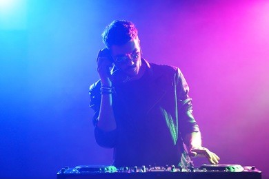 dj playing music at mixer on colorful foggy background