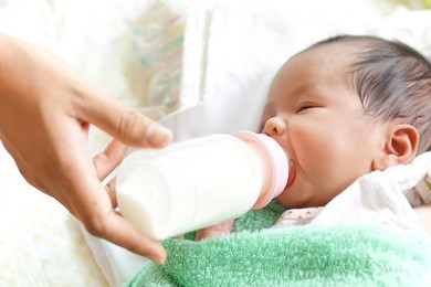 asian newborn baby drinking milk from bottle