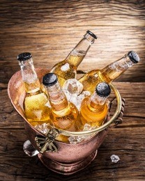 cold bottles of beer in the brazen bucket on the wooden table.