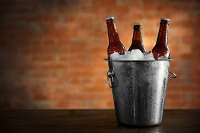 brown glass bottles of beer in ice-pail on brick wall background