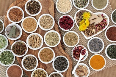 large herb selection used in female alternative herbal medicine on an olive wood board over bamboo background.