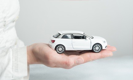 car insurance. automobile collision damage waiver concepts. with protective gesture and icon of car. protection of car. business concept. toy car and hand  isolated on white